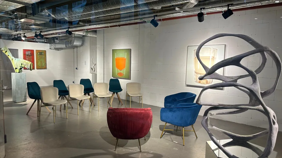 The gallery set up for a talk: rows of chairs and velvet armchairs between paintings and a large sculpture