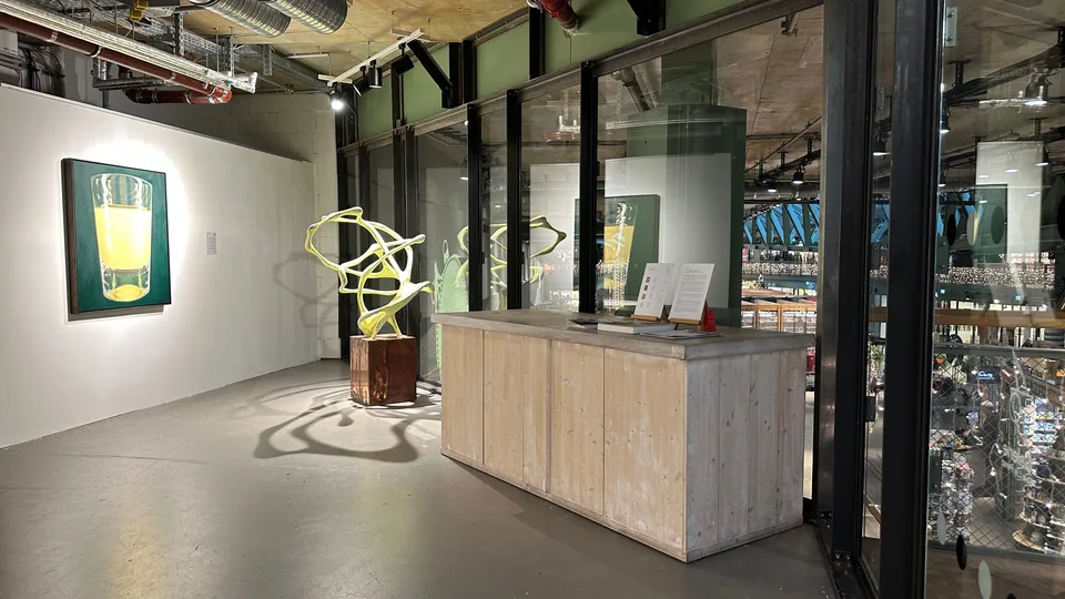 Reception counter by the glass front, with a painting and a sculpture