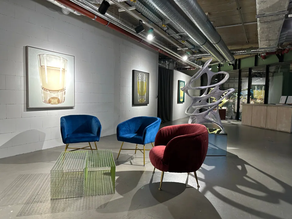 Lounge corner with blue and red velvet armchairs, a glass table, paintings and a sculpture